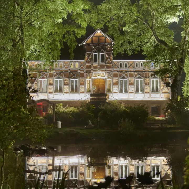 Gutshaus von Gut Steimke spiegelt sich nachts im Wasser